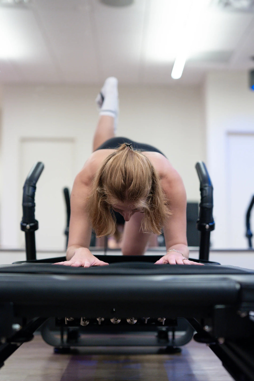 Woman stretching on a Pilates reformer during a class at FlowCorps — a top pick for pilates near me in Charlotte.