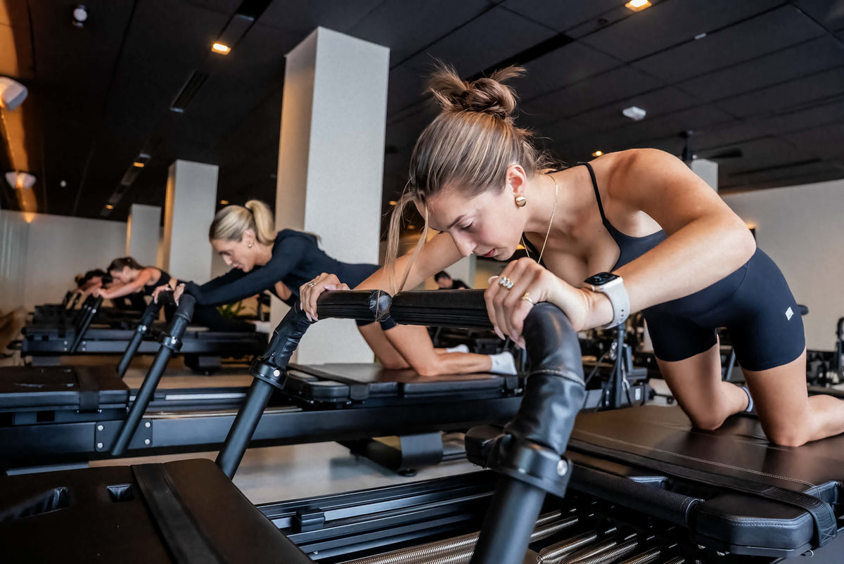 Reformer Pilates class near me at FlowCorps. Group session with reformer machine and weights for core strength and full-body sculpting
