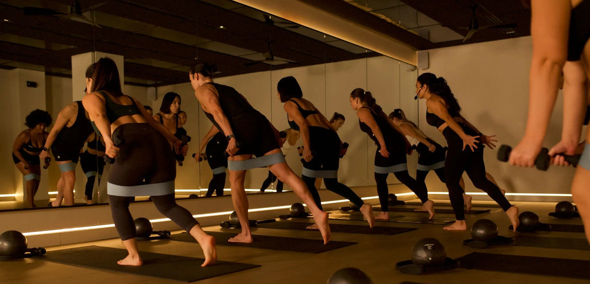Group practicing unheated Mat Pilates during a high-intensity, low-impact Pilates class at a Durham, NC fitness studio.