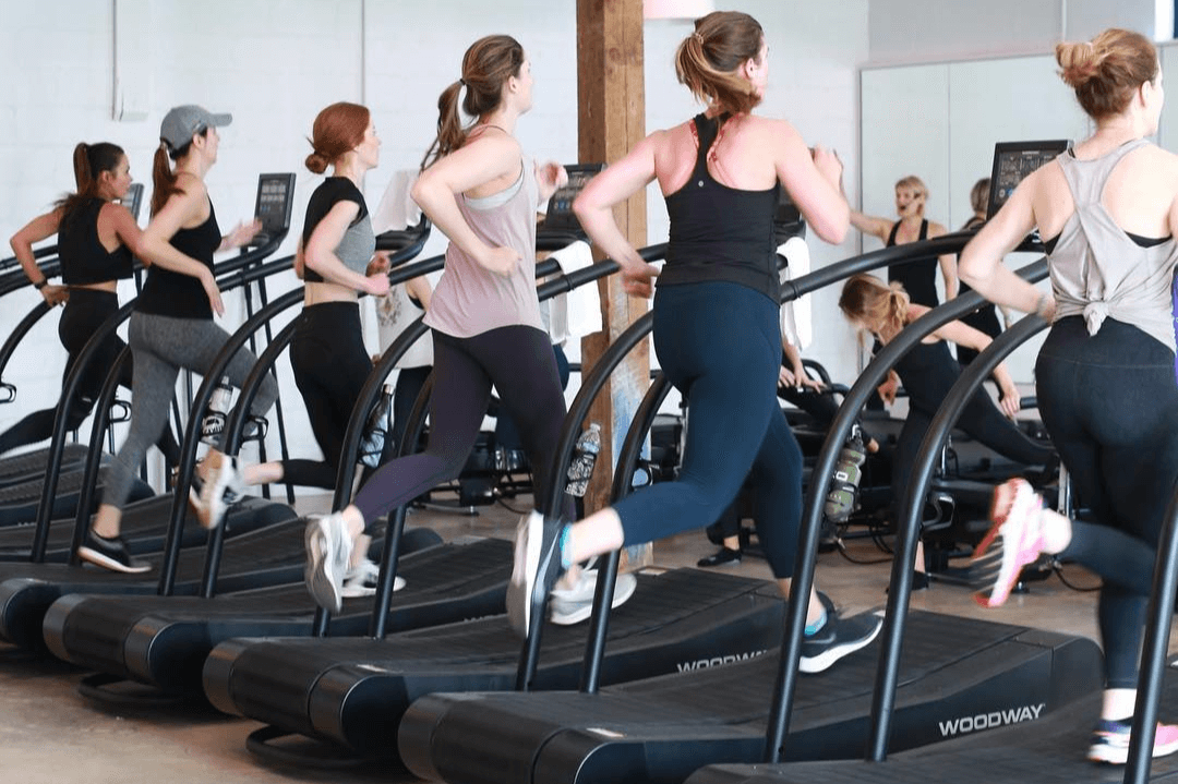 Group of women walking and running on treadmills during a TreadX cardio class at FlowCorps studio
