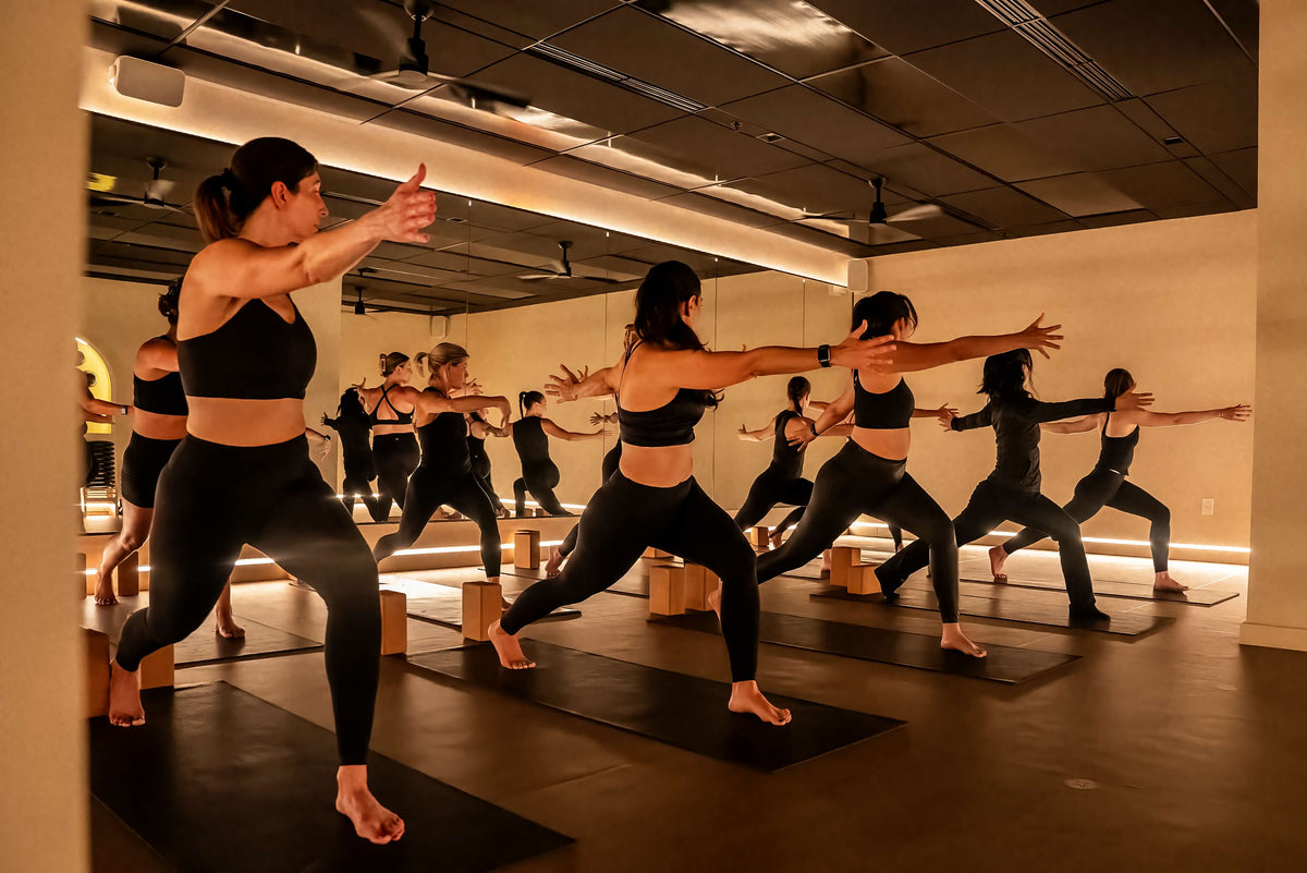 Full mat Pilates studio moving through a yoga rhythm class at
FlowCorps Durham.